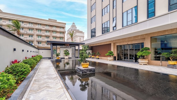 A modern building with a reflective water feature and potted plants. - Holiday Inn Express Zhuhai Guishan Island (Zhuhai)