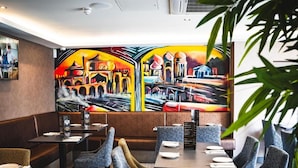 A restaurant interior with booths, tables, and a large mural on the wall. - Deira Hotel & Apartments (Prestwick)