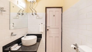 Casa de banho com lavatório branco, espelho, sanita e porta, além de um porta-toalhas.