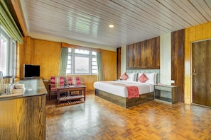 A hotel room with a bed, a desk, a TV, and a window with curtains. - Summit Tashi Ghang Heritage Resort Pelling (Gyalshing)