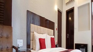 Een hotelkamer met een bed, nachtkastje, stoel en een klein tafeltje.
