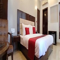 Una habitación de hotel con cama, mesita de noche, una silla y una pequeña mesa.