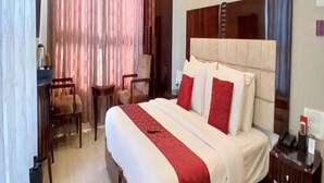 Een hotelkamer met een groot bed, een bureau, twee stoelen en een nachtkastje.