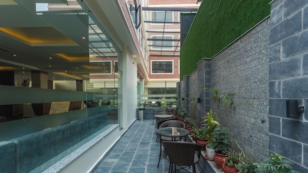 A modern indoor space with a glass railing, seating area, and potted plants. - Hotel Crystal Pashupati (Kathmandu)