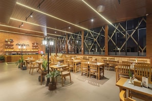En restaurant med træborde og -stole, en murstensvæg med en disk og store vinduer.