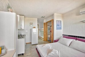 Una camera d'albergo con un letto, angolo cottura, bagno e vista sul mare.