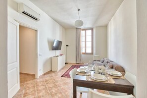 A dining area with a table set for four, a television on the wall, and a window with curtains. - Via dei Servi – Vista Duomo, centro di Firenze (Florence)