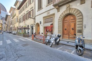 A street with parked scooters, a gelateria, and a row of buildings with arched windows and doors. - Via dei Servi – Vista Duomo, centro di Firenze (Florence)