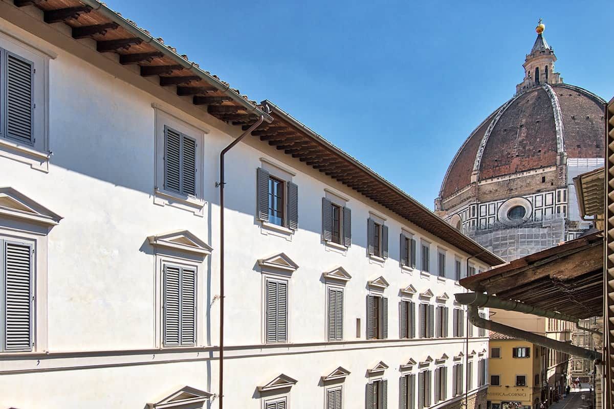 A historic building with multiple windows and a dome in the background.