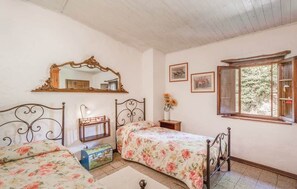 Ein Schlafzimmer mit zwei Betten, einem großen Spiegel, einem Fenster und einem kleinen Tisch mit Blumen.