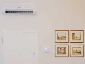 A room with a white door, a wall-mounted air conditioner, and four framed pictures. - In the Heart of Florence, Just a Stone's Throw from the Duomo (Florence)
