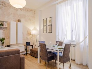 A dining area with a table set for four, a sofa, a lamp, and a radiator. - In the Heart of Florence, Just a Stone's Throw from the Duomo (Florence)