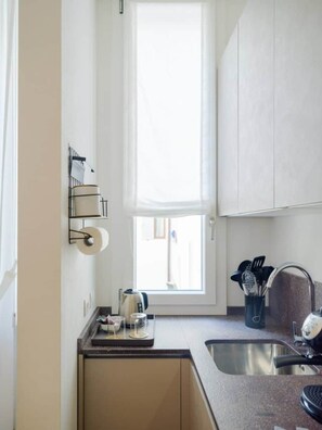 Une petite cuisine avec une fenêtre, un évier et un plan de travail.