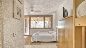 Een slaapkamer met een bed, een houten garderobe, een raam en een plafondventilator.