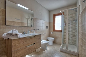 Ein modernes Badezimmer mit einem hölzernen Waschtisch, einer Duschkabine aus Glas, einer Toilette und einem großen Spiegel.