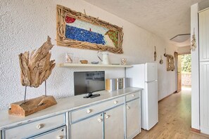 A kitchen with a rustic aesthetic, featuring a wooden-framed artwork, a television, and a white refrigerator. - Comfort and relaxation in the heart of the Costa Smeralda (Cugnana Verde)