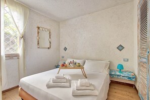 A bedroom with a bed, towels, a tray with breakfast items, and a bedside table with a lamp. - Comfort and relaxation in the heart of the Costa Smeralda (Cugnana Verde)