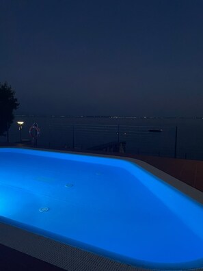 A swimming pool with a view of the sea at night. - Gardazzurro—Vacation Rental on Lake Garda with a Pool & Tennis Court (Padenghe Sul Garda)