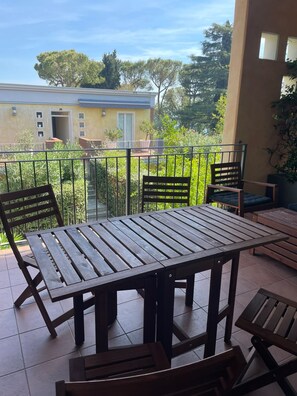 A balcony with a wooden table and chairs, a view of a building, and a railing. - Gardazzurro—Vacation Rental on Lake Garda with a Pool & Tennis Court (Padenghe Sul Garda)