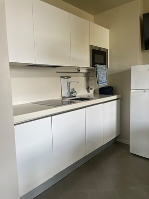 A modern kitchen with white cabinetry, a stainless steel range hood, a built-in sink, and a refrigerator. - Gardazzurro—Vacation Rental on Lake Garda with a Pool & Tennis Court (Padenghe Sul Garda)