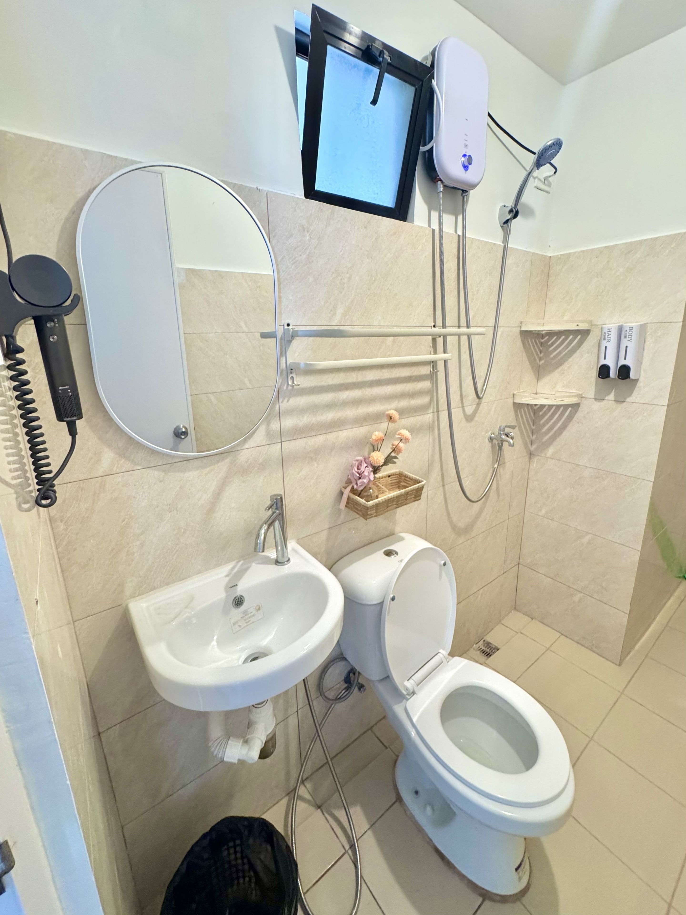 A bathroom with a toilet, sink, mirror, and a shower.