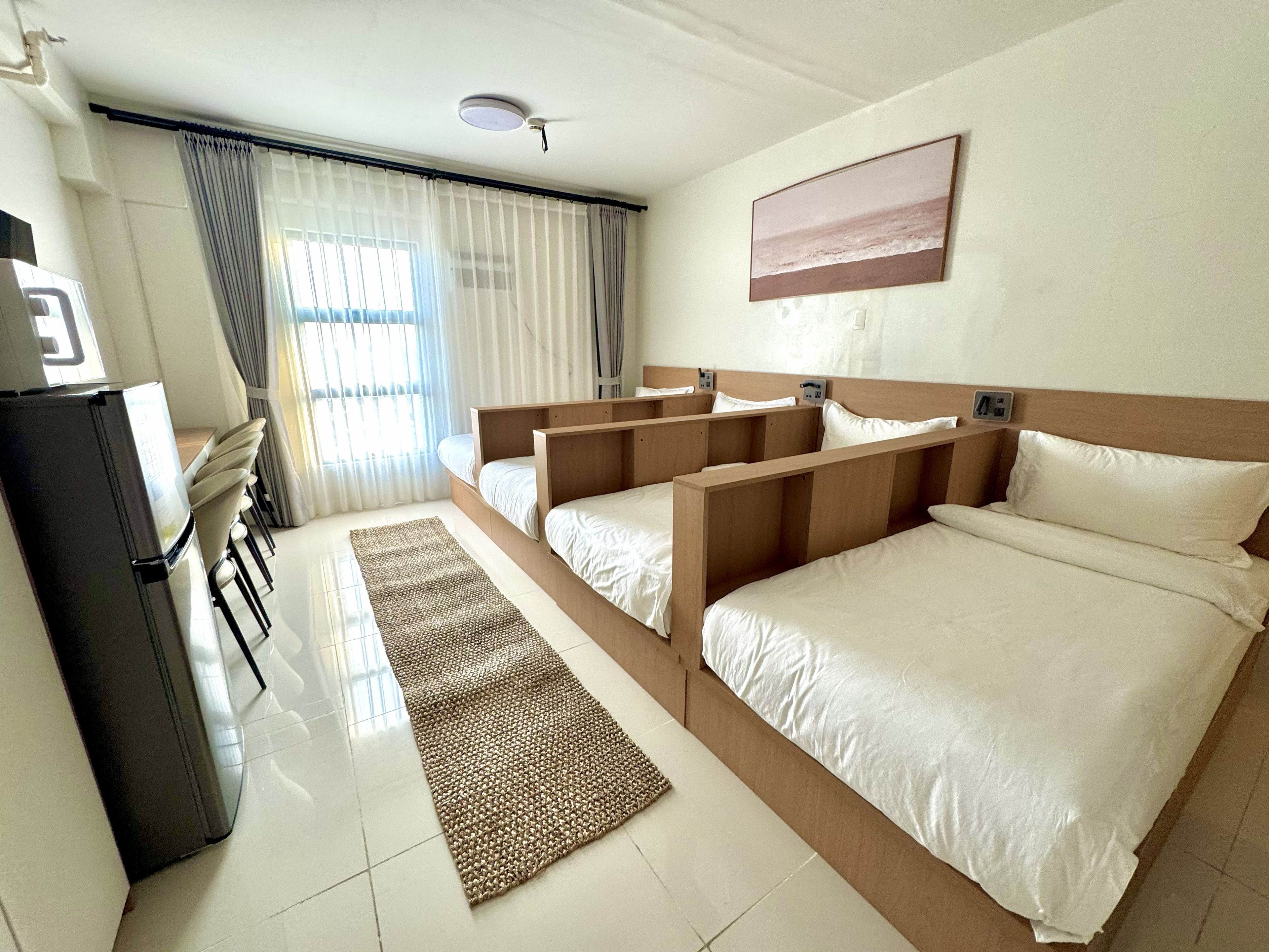 A hotel room with a bed, a desk, and a refrigerator.