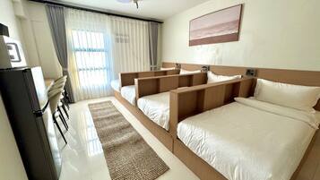 A hotel room with a bed, a desk, and a refrigerator.