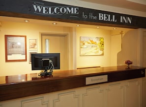 Un comptoir d’accueil surmonté d’une enseigne indiquant : « Bienvenue à l’hôtel Bell Inn ».