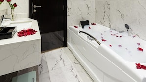 A bathroom with a bathtub, a sink, and a door. - Gardn Millennium Hotel Abha (Abha)