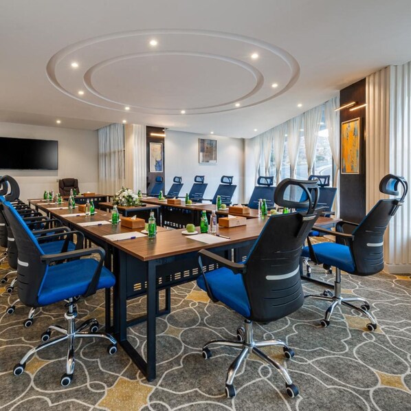 A conference room with a long table, multiple chairs, and a television screen. - Gardn Millennium Hotel Abha (Abha)