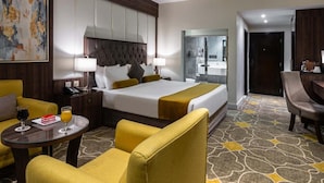 A hotel room with a bed, a desk, a chair, and a small table with drinks. - Gardn Millennium Hotel Abha (Abha)