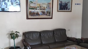 A living room with a leather sofa, a coffee table, a potted plant, and two framed pictures on the wall. - Hotel Tarik (Fnideq)