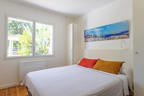 Ein Schlafzimmer mit Bett, Fenster, Heizkörper und einem Bild an der Wand.