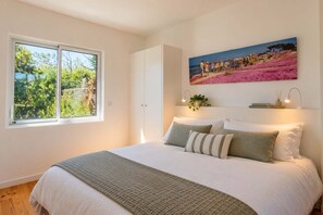 Une chambre à coucher avec un lit, une fenêtre, un tableau et une plante.