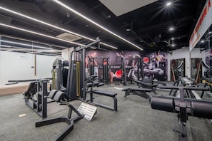 Un gimnasio con diverso equipo de ejercicio, incluyendo máquinas de pesas y bancos.