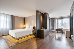 Een moderne hotelkamer met een groot bed, een bureau en uitzicht op de stad.