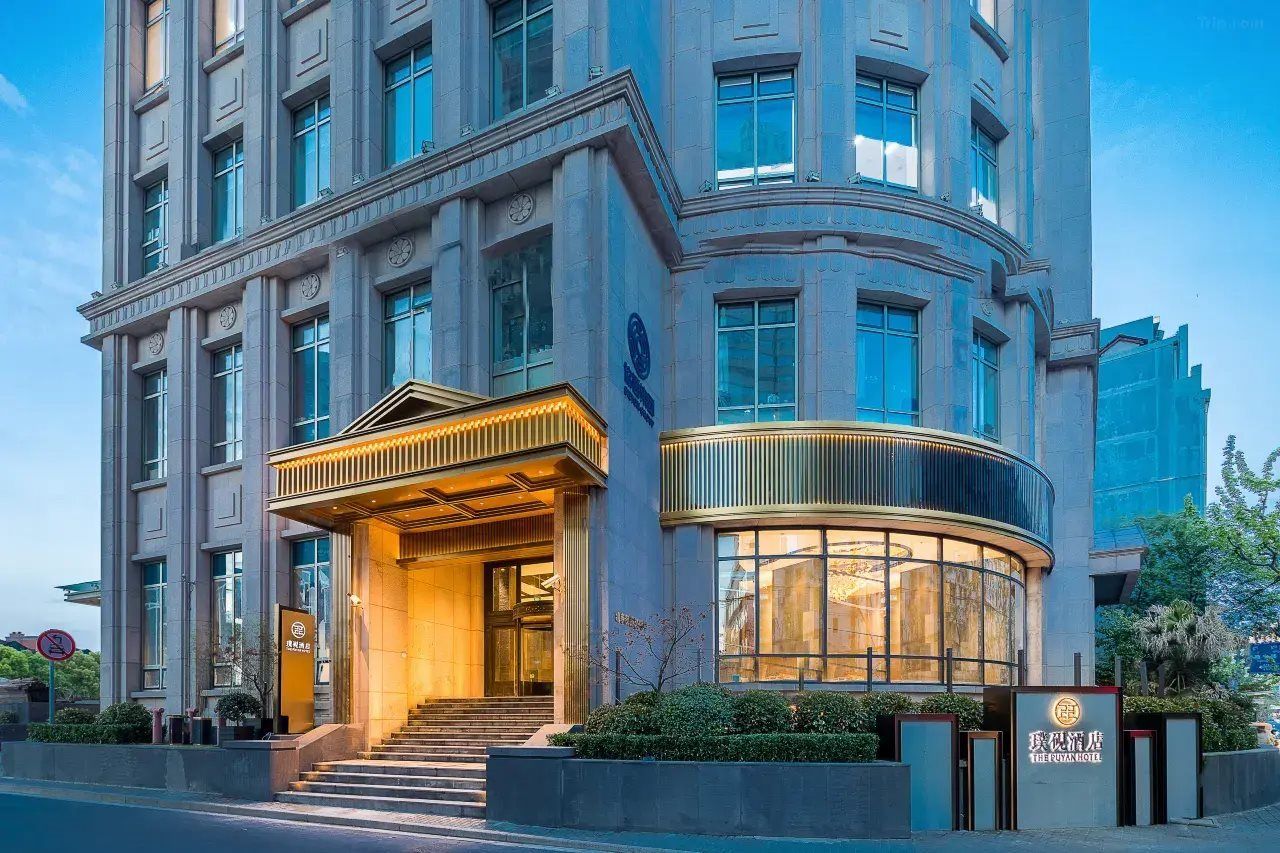 A multi-story hotel with a grand entrance, a curved glass facade, and a sign indicating 'The Guanjian Hotel.'