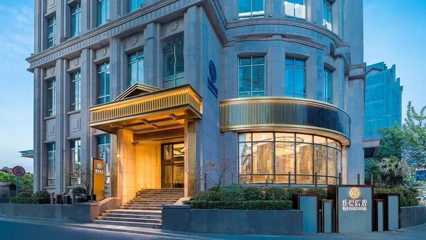 Monikerroksinen hotelli, jossa on vaikuttava pääsisäänkäynti, kaareva lasijulkisivu ja kyltti, jossa lukee: ”The Guanjian Hotel”.