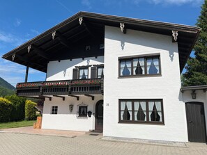 A two-story building with a balcony, large windows, and a door. - Apartment with a balcony (Inzell)