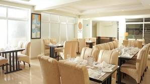 A dining area with multiple tables and chairs, large windows, and artwork on the walls. - Faletti's Express - Islamabad (Islamabad)