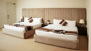 A hotel room with two beds, each with a headboard, bedside tables, lamps, and decorative pillows. - Faletti's Express - Islamabad (Islamabad)