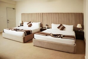 Une chambre d’hôtel avec deux lits, chacun doté d’une tête de lit, de tables de chevet, de lampes et de coussins décoratifs.