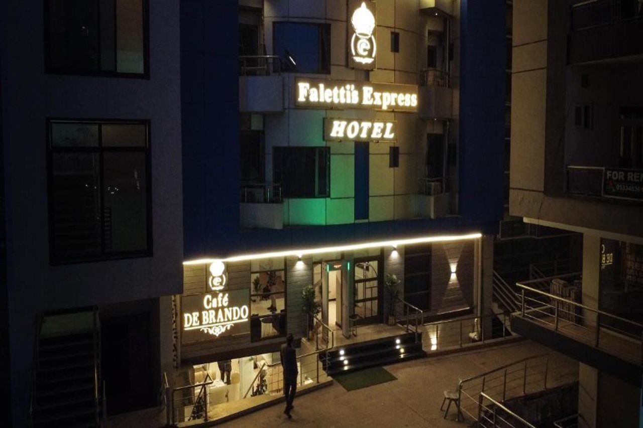 A hotel with a sign for 'Palettis Express Hotel' and a cafe named 'Cafe De Brando' below it.