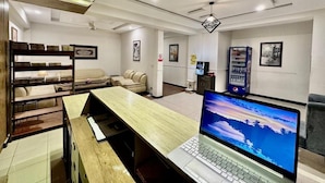 A hotel lobby with a wooden reception desk, a laptop, seating area, and a vending machine. - Faletti's Express - Islamabad (Islamabad)