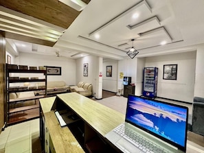 Un hall d’hôtel avec un comptoir d’accueil en bois, un ordinateur portable, un espace salon et un distributeur automatique.
