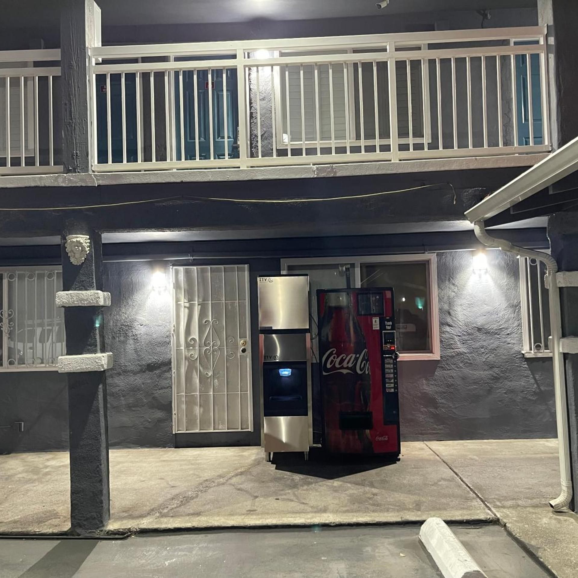 A building with a gated entrance, a Coca-Cola vending machine, and a security camera.