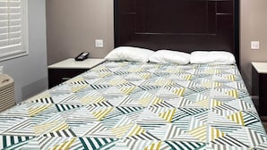 A hotel room with a bed, bedside tables, a nightstand, and a window with blinds. - Studio6 Oakland, CA - San Francisco Berkeley Area (Oakland)