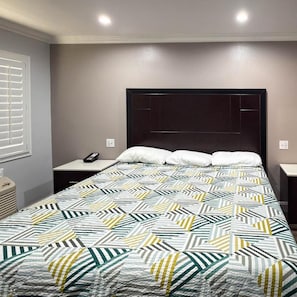 Ein Hotelzimmer mit Bett, Nachttischen, einem Fenster mit Jalousien.