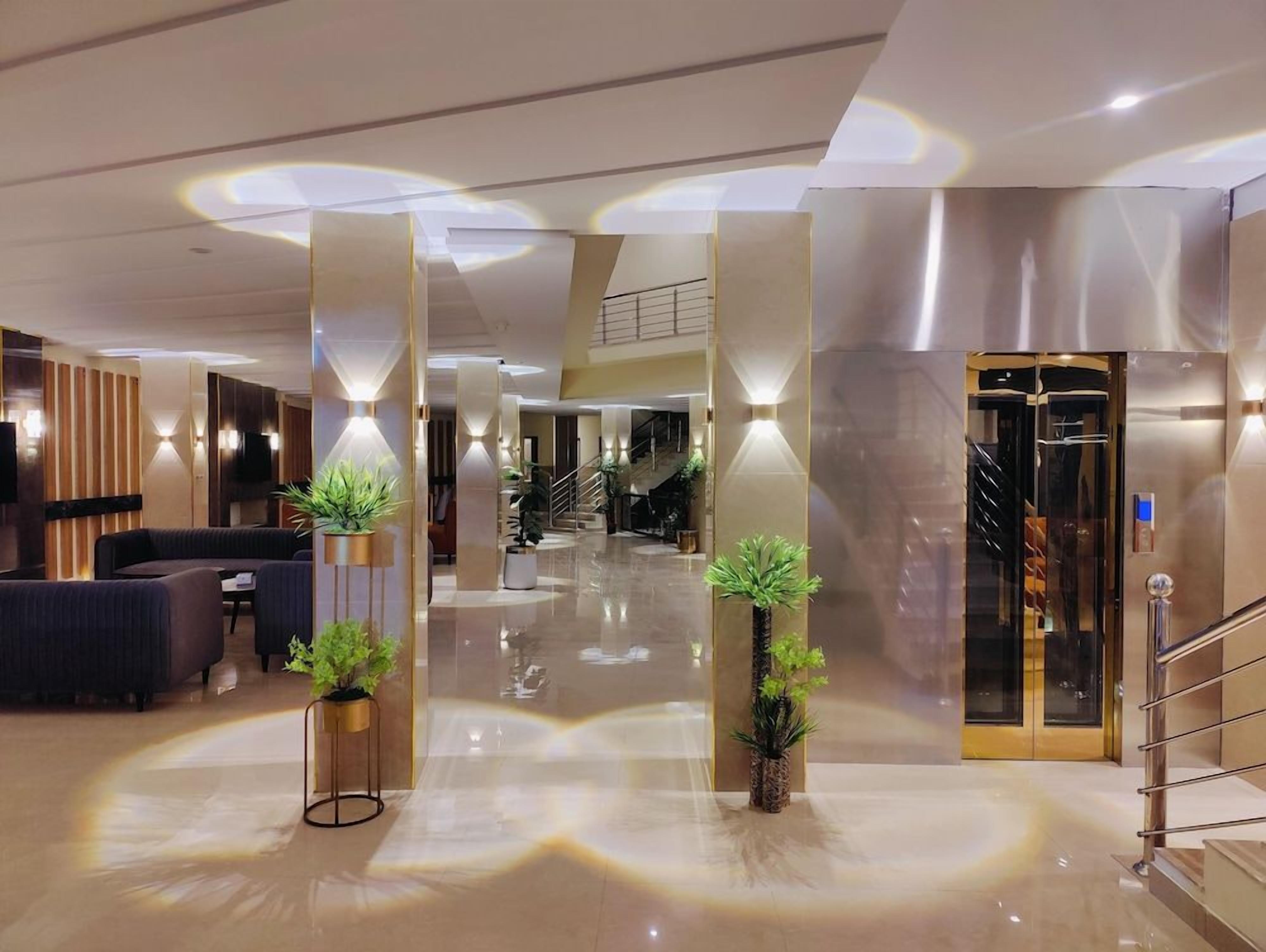 Rebedor modern d'hotel amb escala central, zona de seients i taulell de recepció.