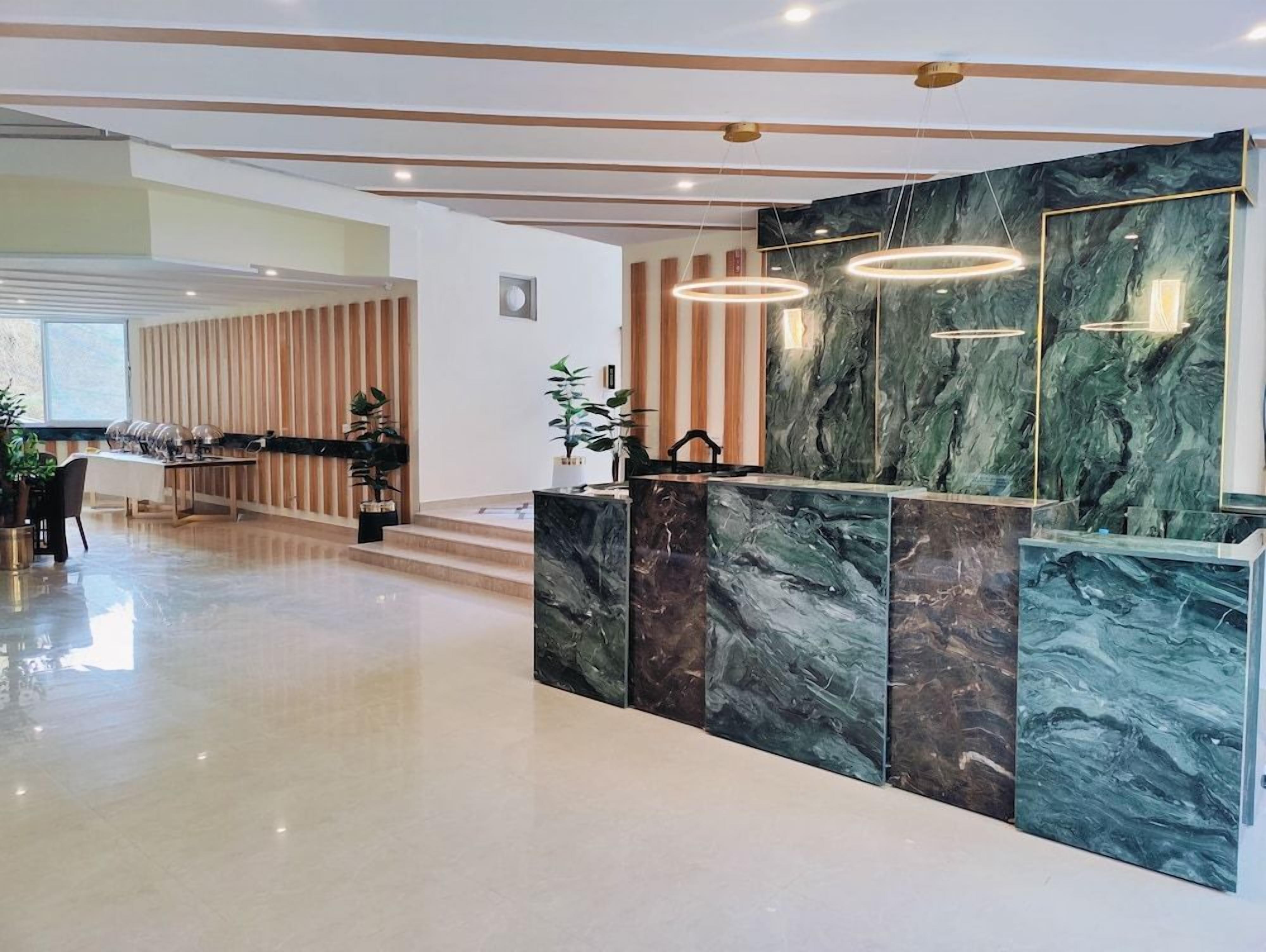 A modern reception area with a marble reception desk, wooden paneling, and pendant lighting.